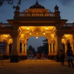 a realistic view of the srimanta sankaradeva kalakshetra entrance gate in guwahati during the evening. warm yellow lights illuminate the traditional assamese architecture. a poster on a stand ne (1)