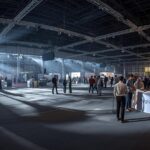 a wide angle interior shot of the maniram dewan trade centre in guwahati being set up for an expo. workers are assembling stage lights and sound equipment. a 'registration' desk is visible in the fo
